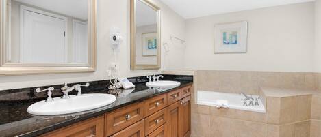 A modern bathroom with two sinks, a large mirror, a bathtub, and a shower.