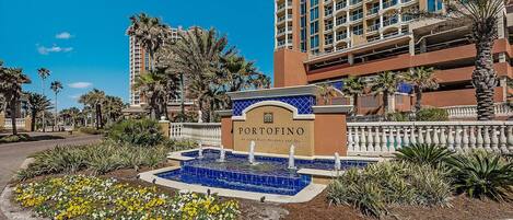Entrada de hotel con un cartel que dice 'PORTOFINO', una fuente y palmeras circundantes.