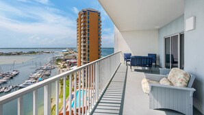 Ein Balkon mit Blick auf ein Hochhaus, eine Marina mit Booten und ein Schwimmbecken.