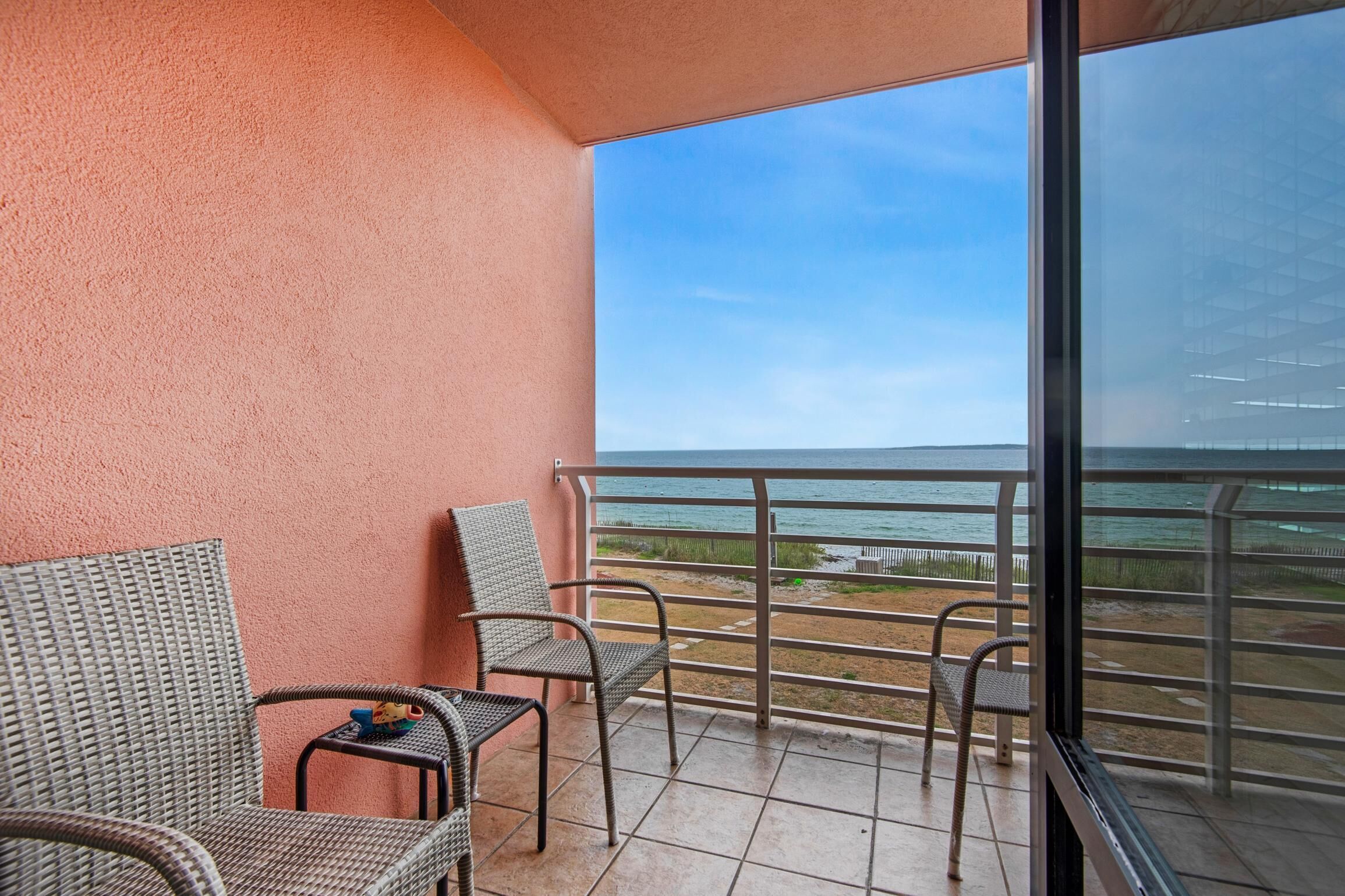 A balcony with wicker chairs and a view of the ocean.