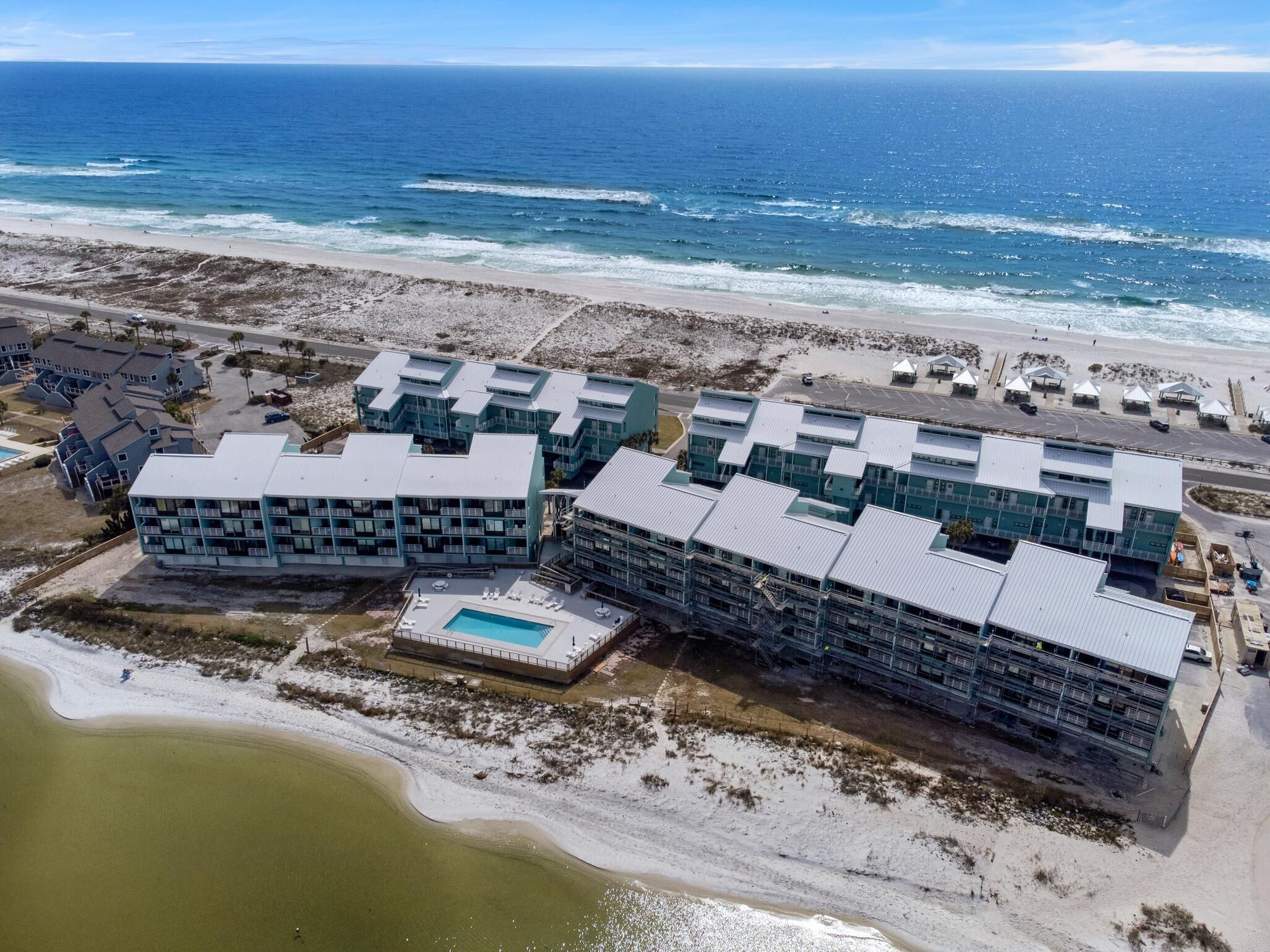 Luchtbeeld van een kusthotel met meerdere gebouwen, een zwembad en een strand op de achtergrond.
