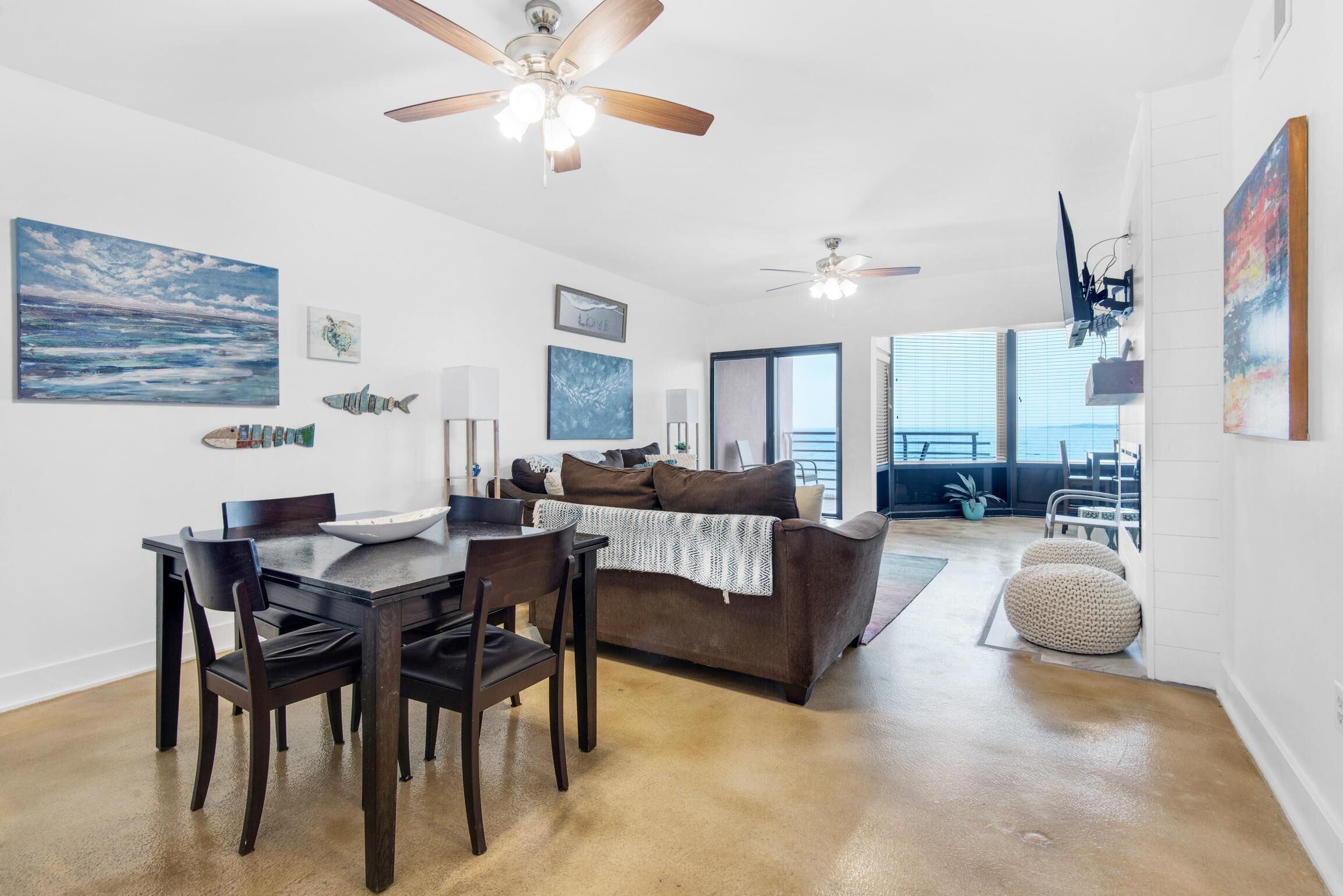 A spacious living room with a dining area, a brown couch, and a ceiling fan.