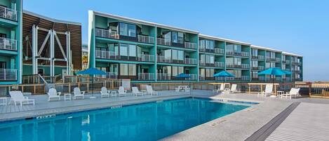 A modern hotel with a pool area, multiple balconies, and outdoor seating.