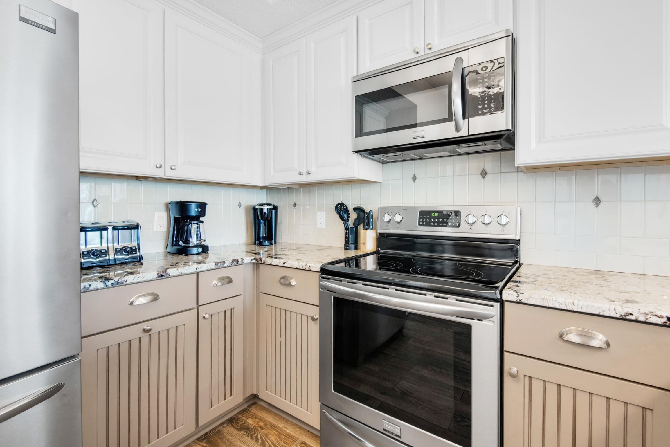A kitchen with white cabinets, a microwave, a stove, and a coffee maker.
