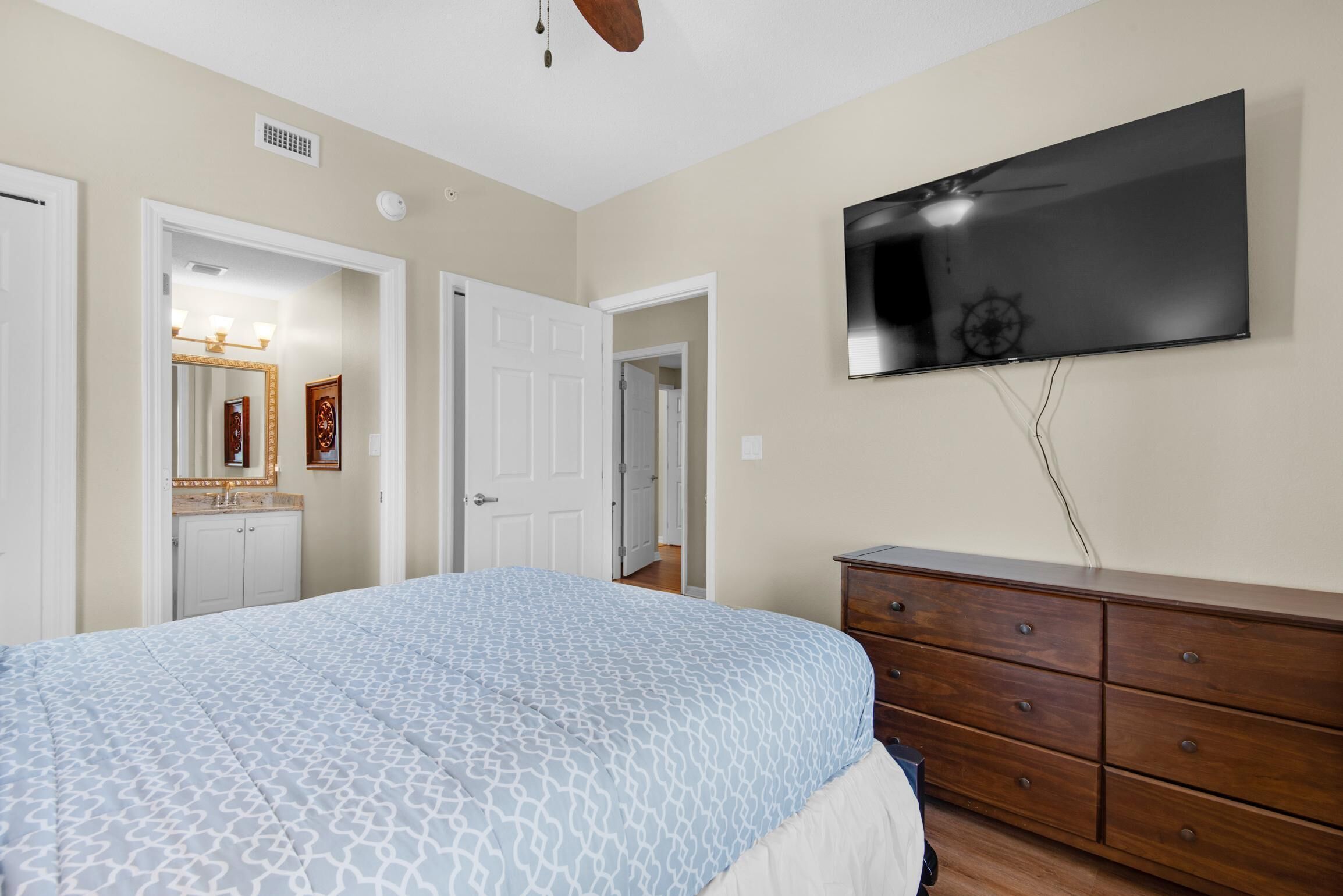 A bedroom with a bed, a dresser, a television, and a door leading to another room.