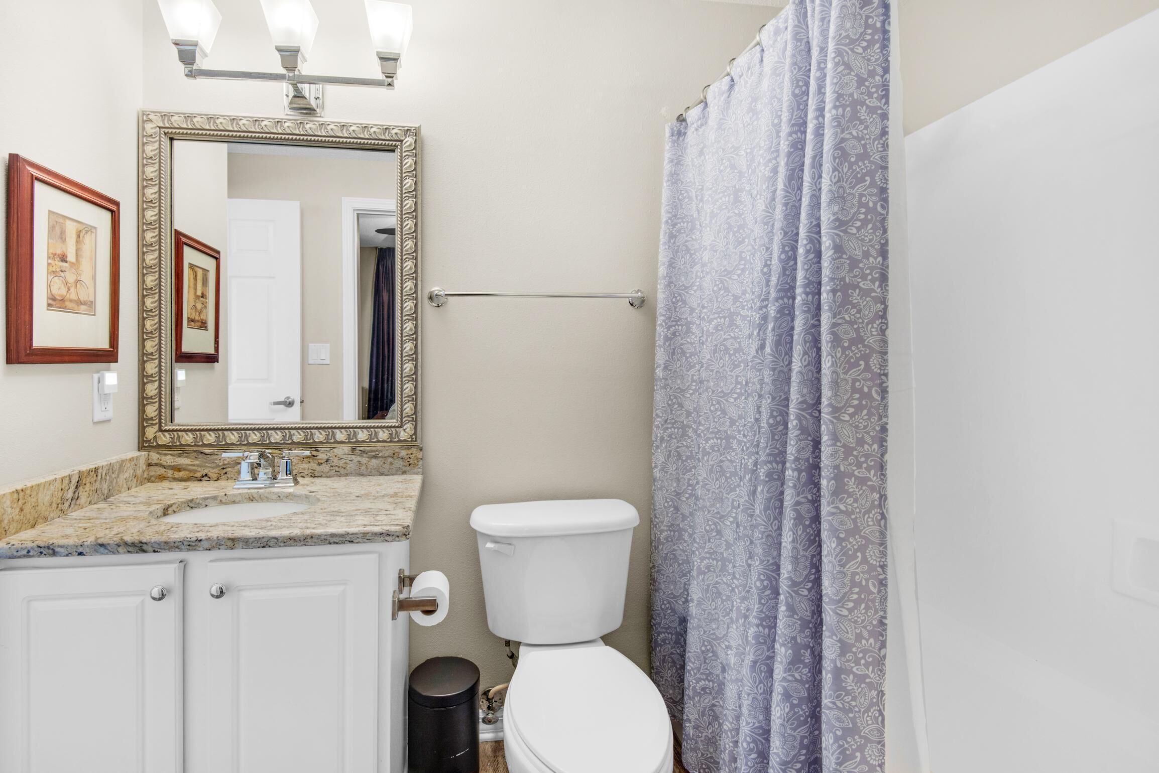 A bathroom with a toilet, sink, mirror, and shower curtain.