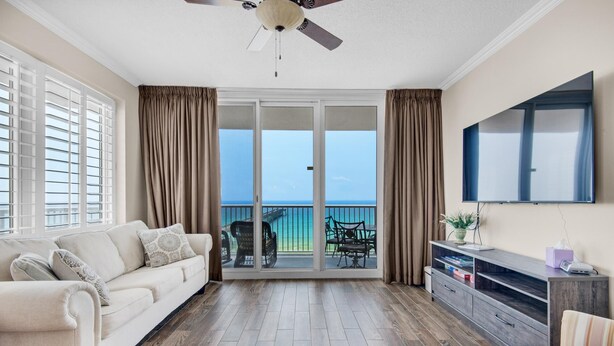 Ein Wohnzimmer mit Sofa, Fernseher und einem Balkon mit Blick.