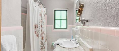 Une salle de bain avec une douche, un lavabo avec un miroir et une fenêtre.