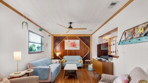A cozy room with a wooden ceiling, a ceiling fan, a bed, a sofa, a small table, and a cabinet. - The Sugar Shack (Pensacola Beach)
