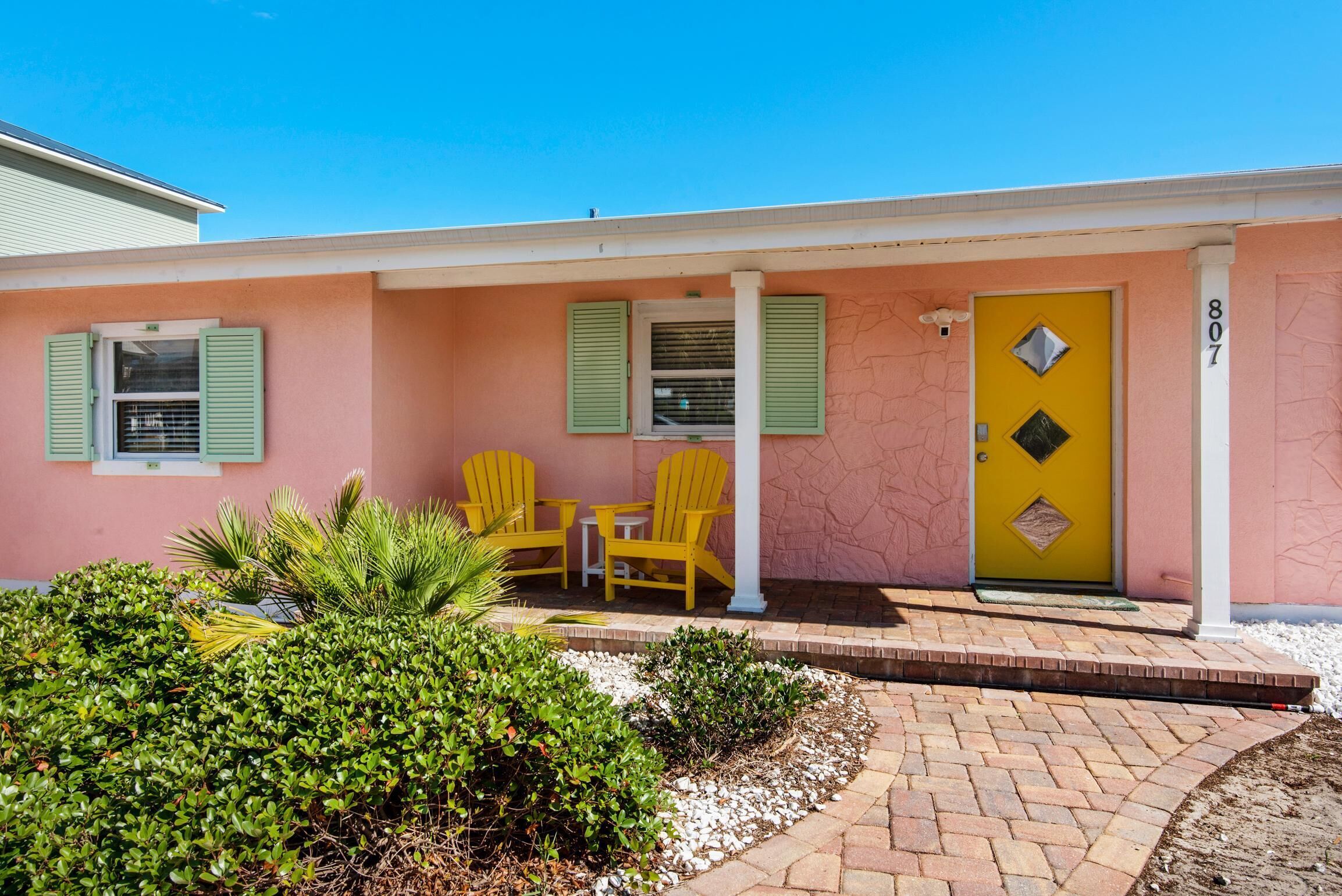 A pink building with a yellow door and green shutters, numbered 807.