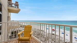 A balcony with a yellow chair overlooking a beach with white sand and a clear blue sky. - Sans Souci Unit 405 (Pensacola Beach)