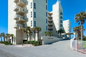 A multi-story hotel with a white facade, balconies, and palm trees in the foreground. - Sans Souci Unit 405 (Pensacola Beach)