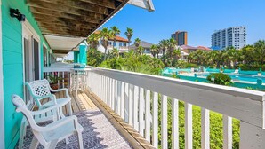 A balcony with white railings, a pool, and palm trees. - Deep Water Cove 103 - OLD (Pensacola Beach)