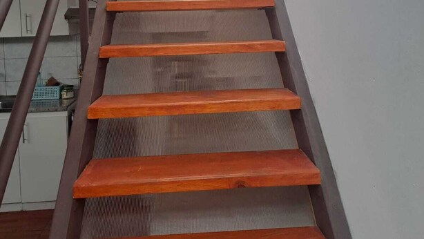 Un escalier en bois avec des rampes en métal menant à l’étage supérieur.