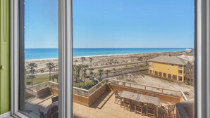 Un balcon avec vue sur la plage et un immeuble jaune.