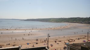A beach with people, a clear sky, and a distant hill. - Waimea Apartment 4 | Best Sea View, Beach Front, Parking, Scarborough (North Yorkshire)
