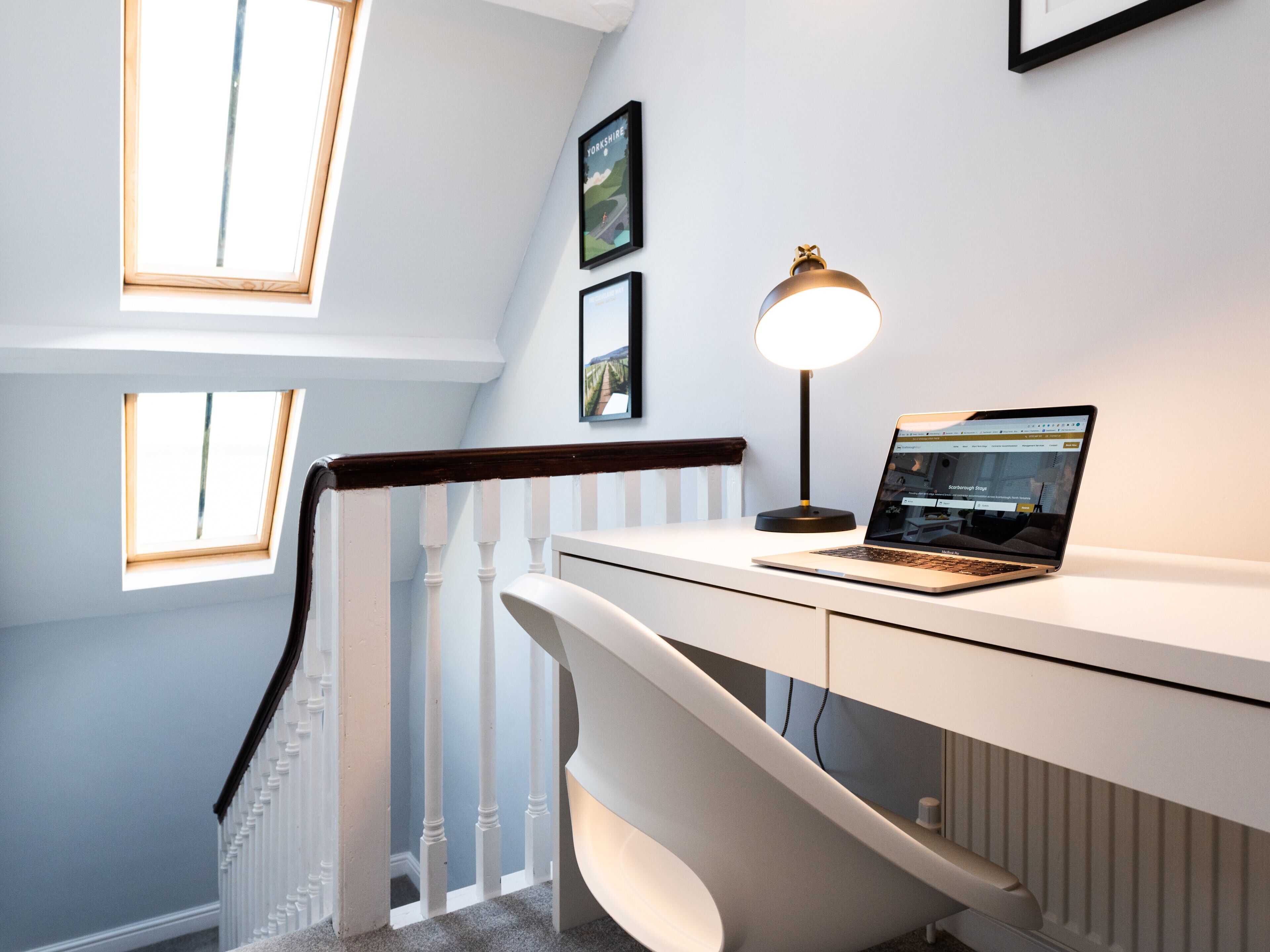 Et moderne kontorrum med et skrivebord, en bærbar computer og en gulvlampe.