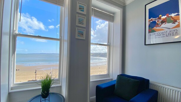 Una habitación con vista a la playa, un sofá azul y un cuadro en la pared.