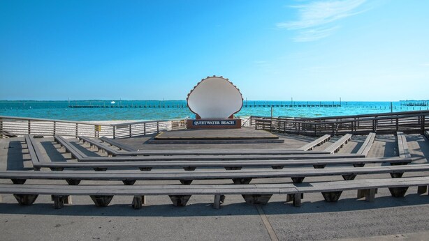 A wooden pier with benches and a sign reading "Quiet Water Beach." - Sand Dollar W-103 (Pensacola Beach)
