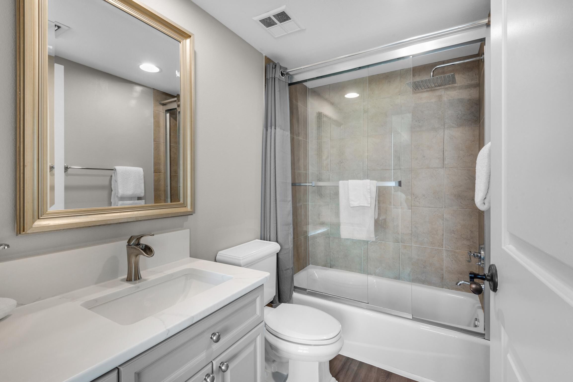 Un baño moderno con lavamanos, inodoro y ducha envuelta en vidrio.
