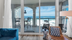 A balcony with a view of the ocean, a blue sofa, and a table with a decorative item.