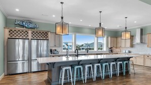 A spacious kitchen with a large island, stainless steel appliances, and a view of the ocean. - Emerald Oasis (Pensacola Beach)