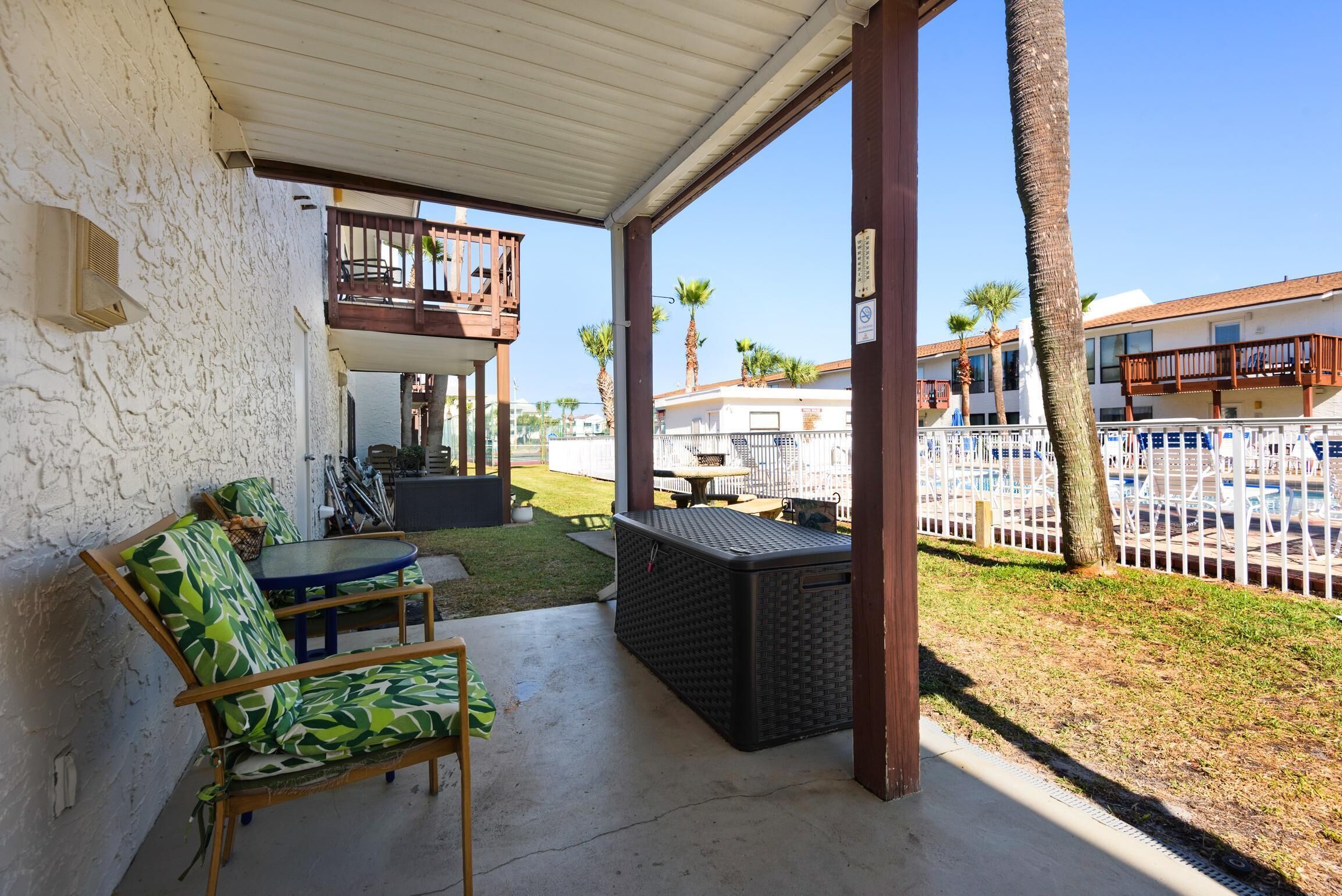 A covered patio with outdoor furniture, a pool, and a view of the surrounding neighborhood.
