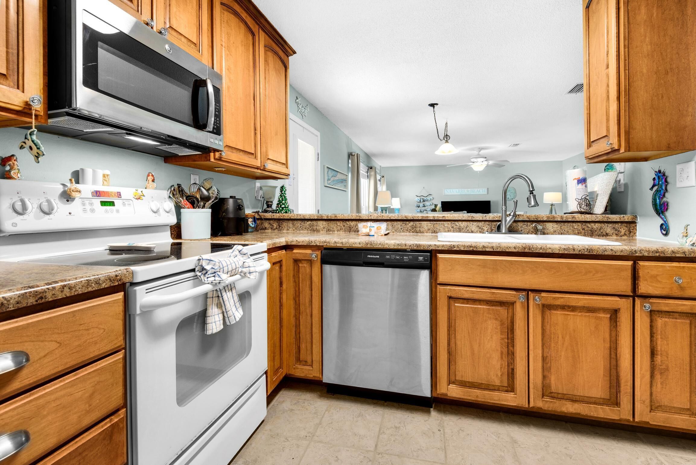 A kitchen with wooden cabinets, a stainless steel microwave, a dishwasher, and a granite countertop.