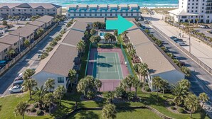 An aerial view of a hotel with a tennis court, parking area, and ocean view. - Beachview 101- Beaches and Moonbeams (Navarre)