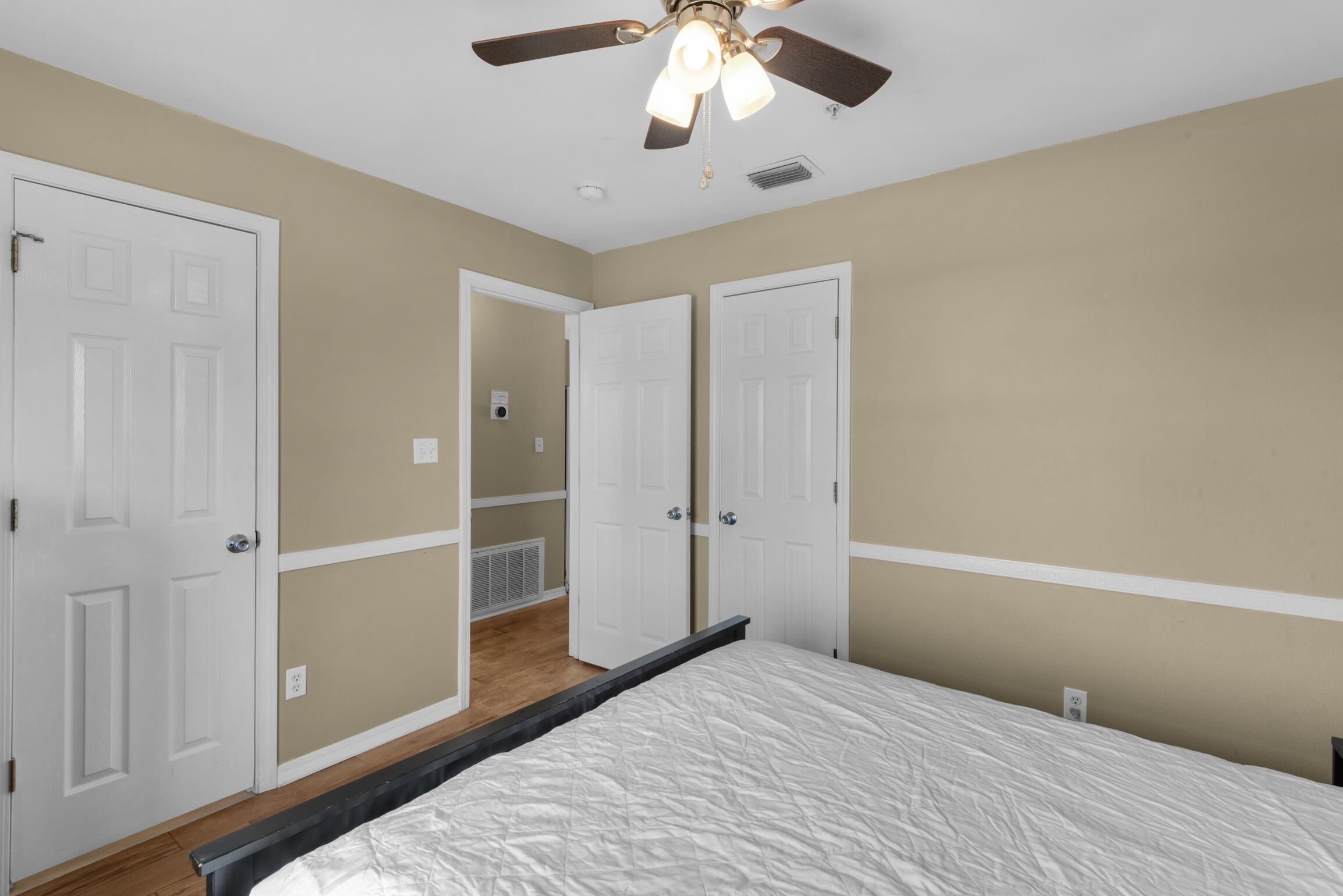 A bedroom with a bed, a ceiling fan, and two white doors.