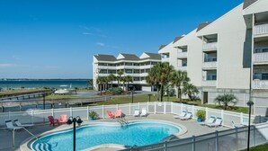 Un hotel con piscina, vallas blancas y vista al océano.