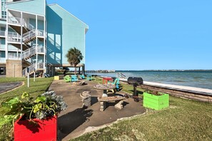 A waterfront patio with outdoor seating, a barbecue grill, and a view of the water. - Baywatch F8 (Pensacola Beach)