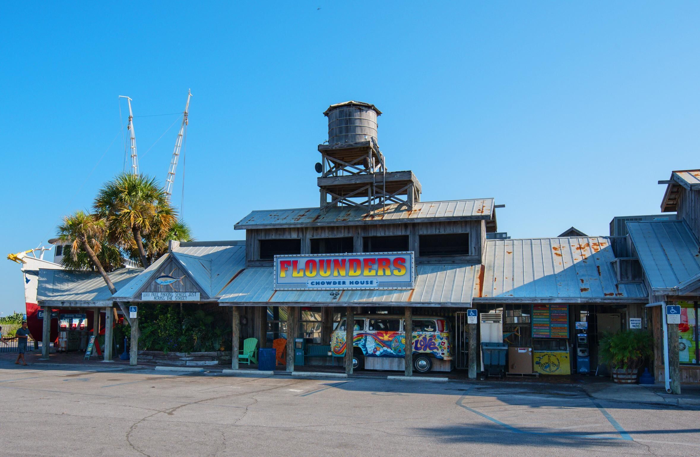 A building with a sign reading "FLOUNDERS Chowder House" and a water tower.