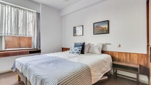 A bedroom with a bed, a bench, a window with curtains, and two framed pictures on the wall. - Home2Book Bright Apt Las Palmas City Center (Las Palmas de Gran Canaria)