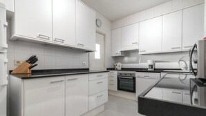 A modern kitchen with white cabinets, a black countertop, and a clock on the wall. - Home2Book Bright Apt Las Palmas City Center (Las Palmas de Gran Canaria)