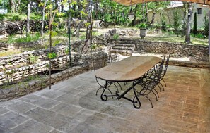 An outdoor patio with a stone table and chairs, surrounded by stone walls and greenery. - Lovely home in Lacoste (Lacoste)