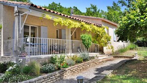 A house with a tiled roof, a balcony with white railings, and a garden with various plants and flowers. - Lovely home in Lacoste (Lacoste)