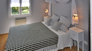 A bedroom with a checkered bedspread, two bedside lamps, a canopy bed, and a window with curtains. - Lovely home in Lacoste (Lacoste)