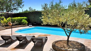 A swimming pool with lounge chairs and a tree in a landscaped area. - Lovely home in Lacoste (Lacoste)