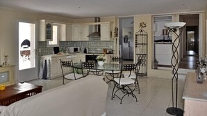 A spacious kitchen with white cabinets, a dining area with a glass table and metal chairs, and a modern refrigerator. - Lovely home in Lacoste (Lacoste)