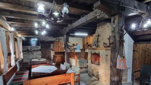 Ein rustikaler Raum mit Holzmöbeln, einem Kamin und hängenden Lampen.