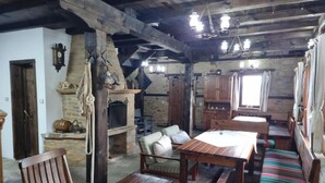 Ein rustikales Interieur mit freiliegenden Holzbalken, einem Steinkamin, Holzmöbeln und einer gemütlichen Sitzecke.