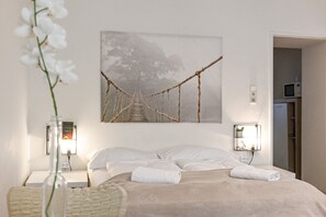A neatly made bed with white linens, a wall-mounted picture of a bridge, bedside lamps, and a small bedside table with a vase of flowers. - Convenient 1BR Apartment @the Heart of Vienna (Vienna)