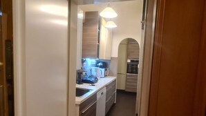A narrow kitchen with a dishwasher, a coffee maker, and a microwave. - Cozy City Center Retreat 2BR Apt. Homelike Comfort (Vienna)