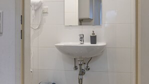 Un baño con lavamanos blanco, un espejo, un teléfono y un inodoro.