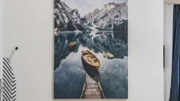 Una pintura de un lago de montaña con un bote de madera en un muelle.