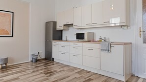Una cocina con armarios blancos, microondas, refrigerador y encimera de madera.