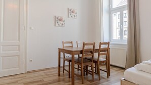 Una habitación con una mesa y sillas de madera, una puerta blanca y una ventana que ofrece vistas a edificios.