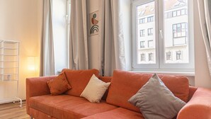 Una habitación con sofá, lámpara y ventana con vista a edificios.