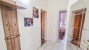 A hallway with a wooden door, a tiled floor, and a tiled wall with artwork.